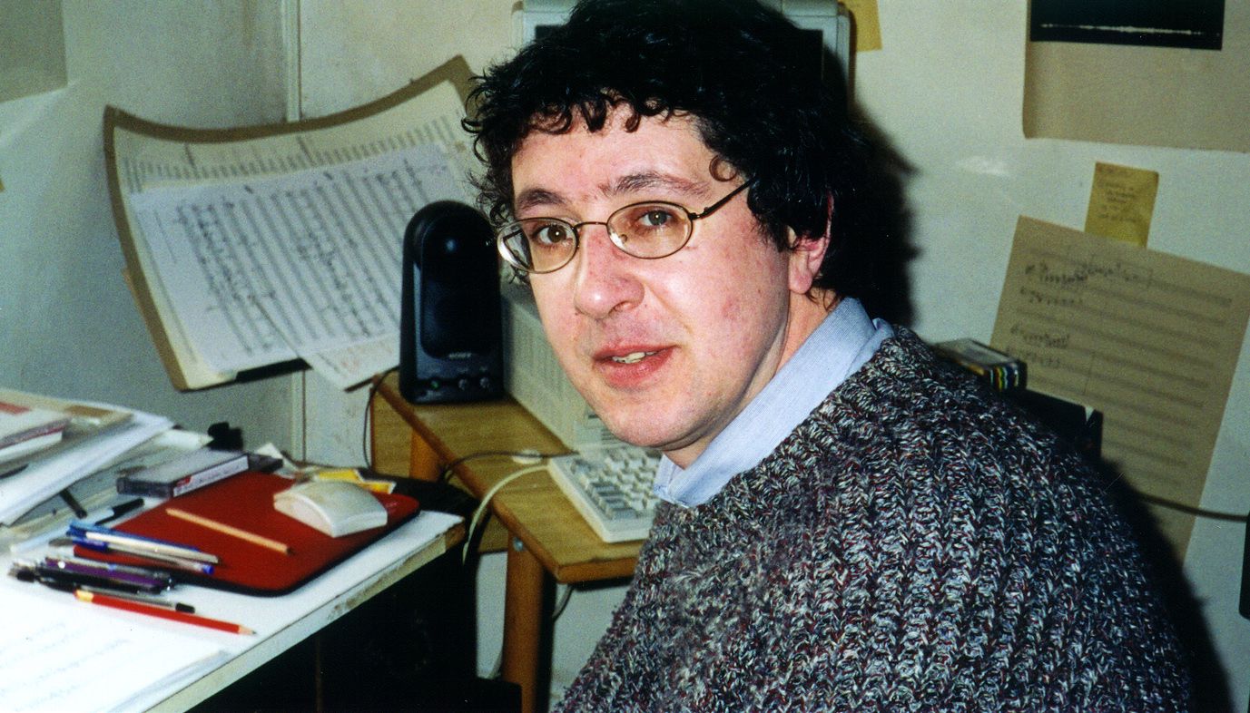 Paul Keenan, composer, in his study surrounded by composition sketches and with a computer in the background.